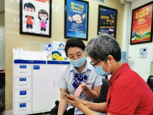 建行成都第六支行，大堂經理為客戶介紹手機銀行“大字”模式